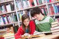 Dwoje uczniów czytających książki przy stole w bibliotece — zdjęcie ilustracyjne