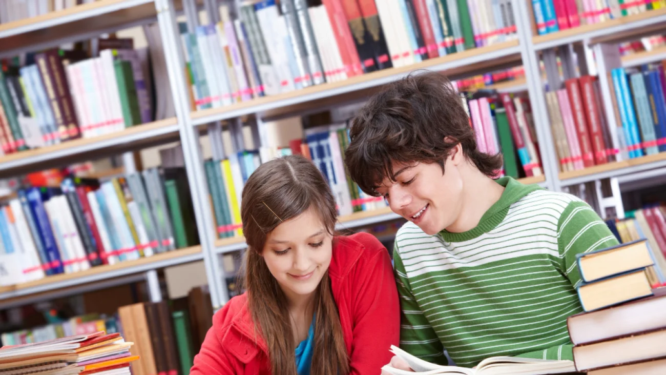 Dwoje uczniów przy książkach w bibliotece — zdjęcie ilustracyjne