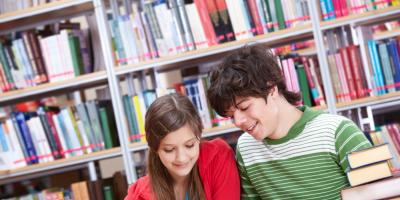 Dwoje uczniów czytających książki przy stole w bibliotece — zdjęcie ilustracyjne