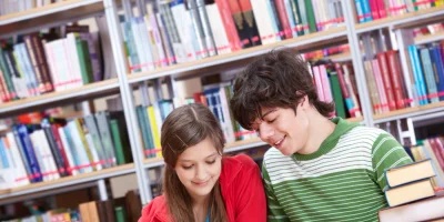 Dwoje uczniów przy książkach w bibliotece — zdjęcie ilustracyjne