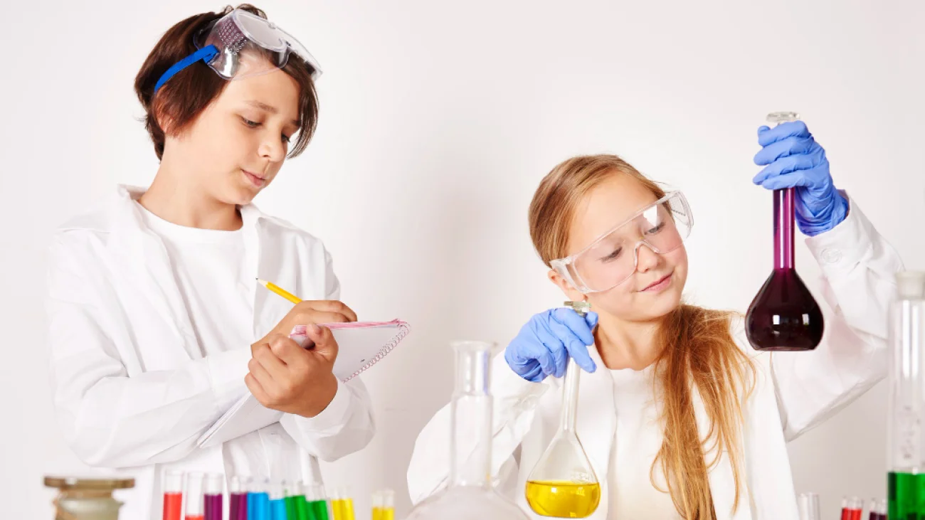 Dwoje dzieci wykonujących doświadczenia z kolorowymi płynami w laboratorium — zdjęcie ilustracyjne