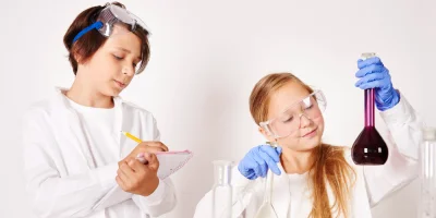 Dwoje dzieci wykonujących doświadczenia z kolorowymi płynami w laboratorium — zdjęcie ilustracyjne